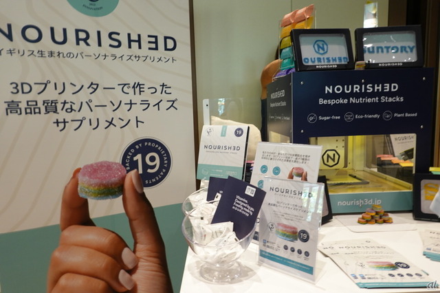 　シグマクシスは、7月27～29日まで、東京ポートシティ竹芝 ポートホールにて、「SKS JAPAN 2023 -Global Foodtech Summit-」をThe Spoonと共同開催した。大企業からスタートアップまで国内外から20社を超える企業が一堂に会し、新素材・新機能食品やパーソナライズフードデバイス、調理ロボット、ヘルスケア／Well-being向上アプリ・サービス等を展示した。

　写真は、イギリス発のスタートアップ企業 Rem3dy Health (レメディ・ヘルス）のブース。3Dプリンタで一人一人の状態に合わせてカスタマイズできるサプリメント・グミ「Nourished（ナリッシュト）」のデモを披露した。まもなく日本でも販売開始予定だ。